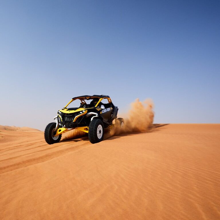 Can-Am Maverick R 2-seater buggy throwing sand on a dune during an Early Bird tour in Dubai